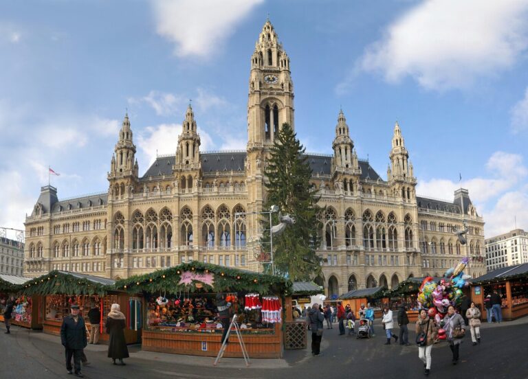 Chalets du Christkindlmarkt alignés devant la façade du Rathaus de Vienne et son grand sapin, par une journée ensoleillée
