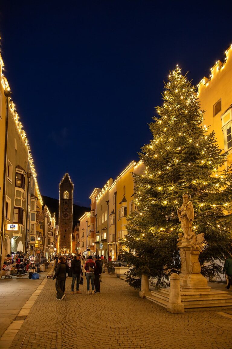 Grand sapin illuminé dans la rue principale de Vipiteno, la tour au loin, la nuit