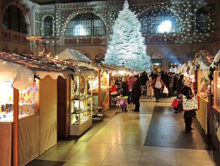 Allée de chalets illuminés du Christkindlimarkt sous la verrière du hall de la gare centrale de Zurich