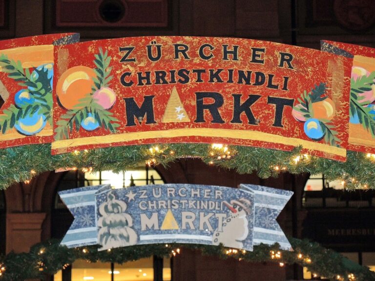 Enseigne peinte « Zürcher Christkindli Markt » ornée de guirlandes, à l’entrée du marché de la gare centrale