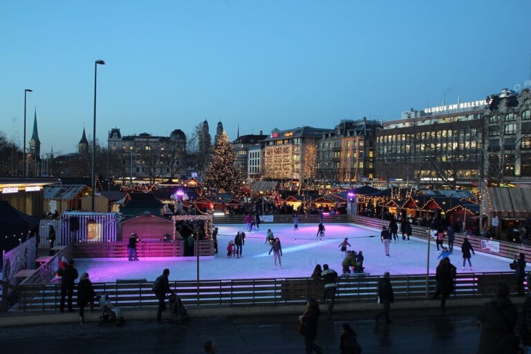 Patinoire éclairée et chalets du village de Noël sur le Sechseläutenplatz, au crépuscule, près de l’Opéra de Zurich