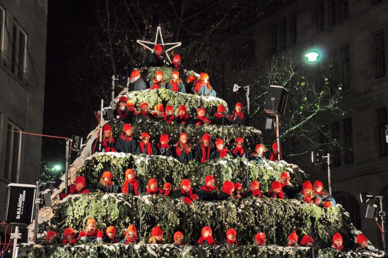 Le Singing Christmas Tree du Werdmühleplatz, gradins en forme de sapin illuminé où se tient un chœur en bonnets rouges