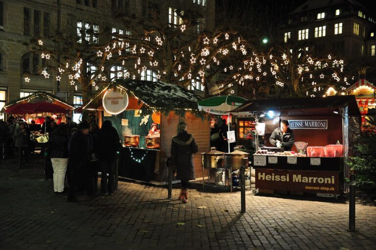 Stands du marché de Noël du Werdmühleplatz la nuit, sous les arbres décorés de lumières