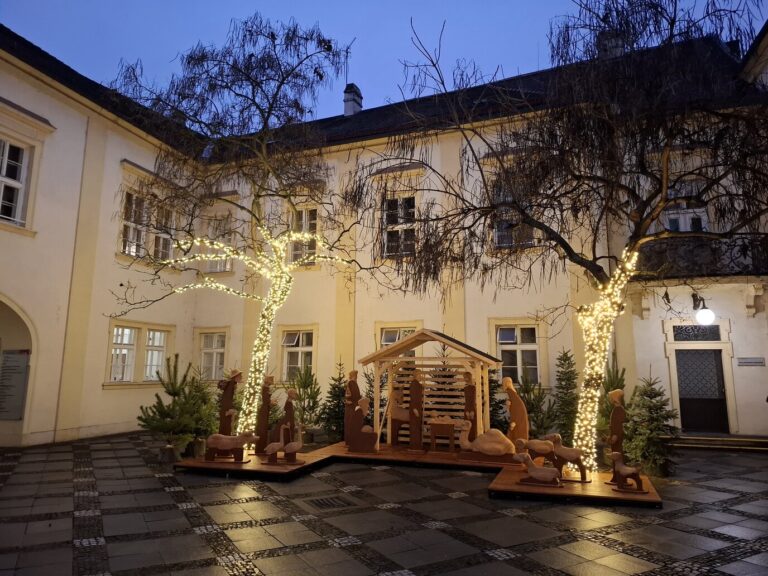 Crèche et arbres illuminés dans la cour à arcades de l’hôtel de ville de Brno, rue Dominikánská, à la tombée de la nuit