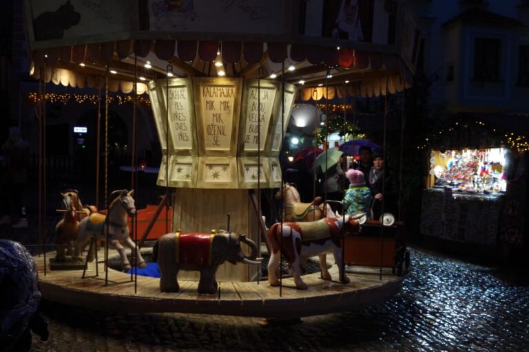 Le manège en bois illuminé du marché de Noël de la place Svornosti à Český Krumlov, sur les pavés mouillés