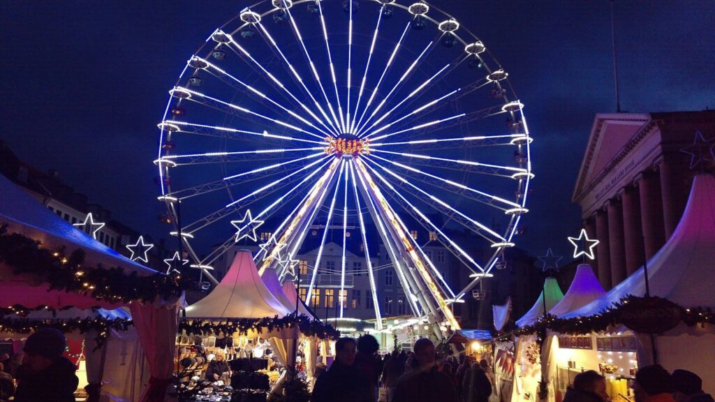 Roue géante illuminée et chalets du marché de Noël de Nytorv à Copenhague, de nuit, à côté du palais de justice