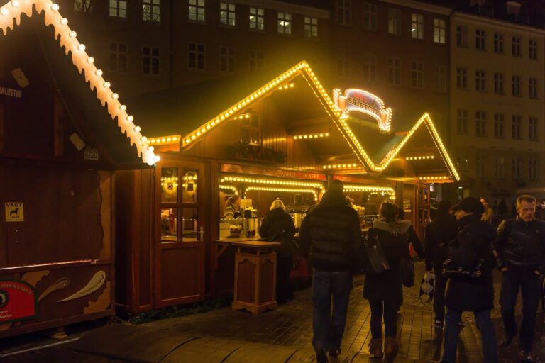 Chalets en bois bordés de guirlandes jaunes au marché de Noël de Copenhague, à la tombée de la nuit