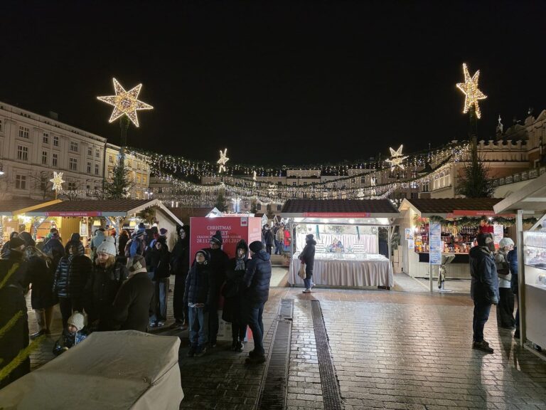Une allée de chalets du marché de Noël du Rynek Główny sous des étoiles lumineuses, de nuit