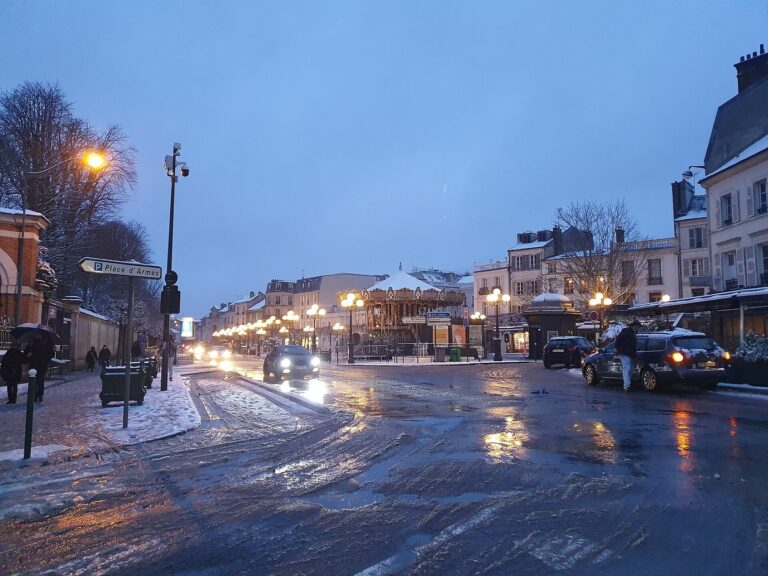 Le carrousel illuminé place Napoléon-Bonaparte, vu depuis la rue Grande mouillée de neige fondue, à la tombée du jour