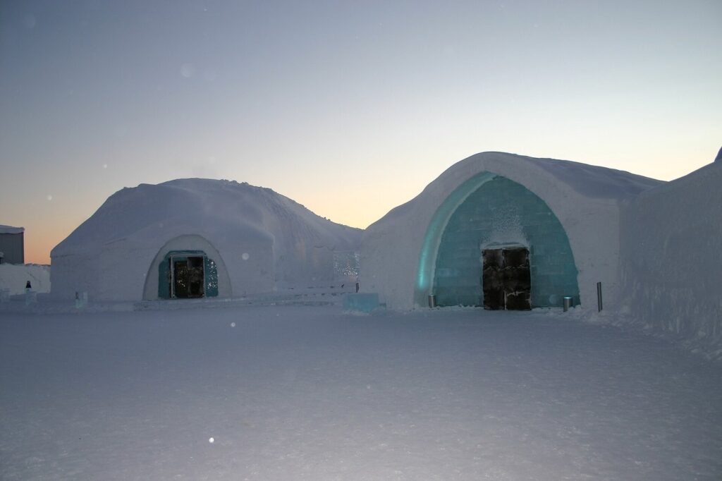 Les voûtes de neige et l’entrée de glace de l’Icehotel de Jukkasjärvi au crépuscule, sur une esplanade enneigée