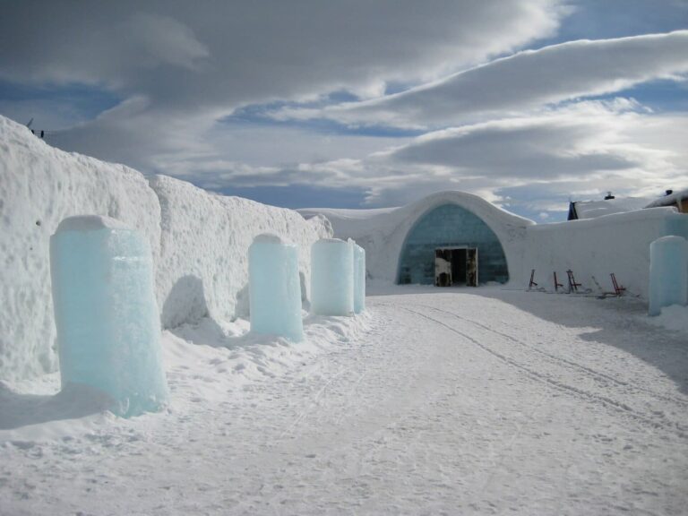 Des colonnes de glace devant les murs de neige, menant à l’entrée de l’Icehotel, sous un ciel nuageux