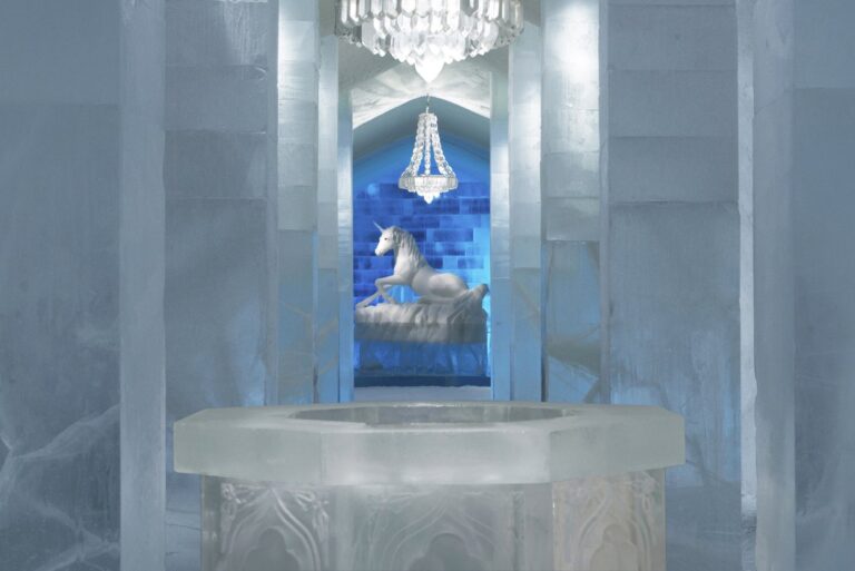 Le grand hall de l’Icehotel avec un lustre, une licorne sculptée dans la glace et une vasque de glace