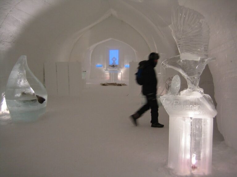 Une galerie de glace avec des sculptures translucides et un autel éclairé de bleu au fond