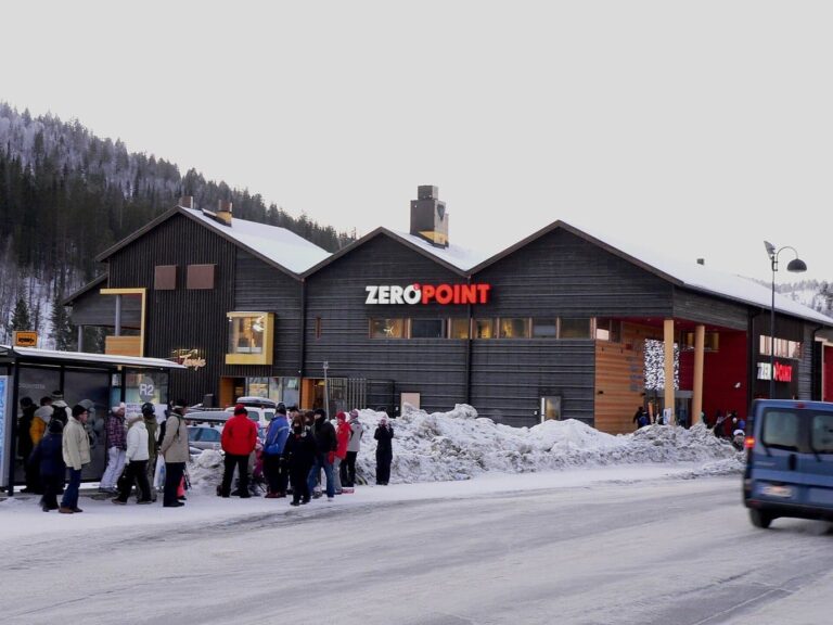 Le bâtiment Zero Point au pied des pistes de Levi, avec des promeneurs sur le trottoir enneigé
