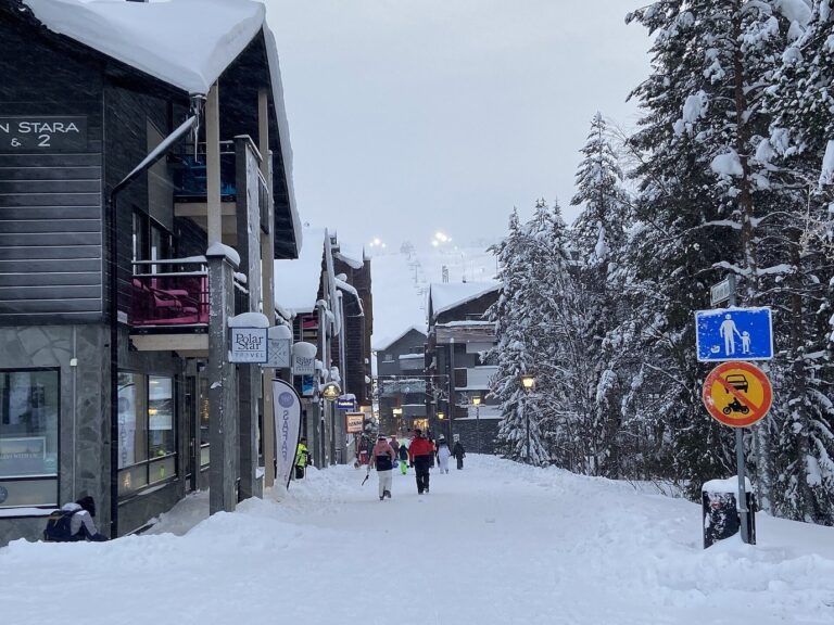La rue Torikuja de Levi bordée de chalets et de sapins chargés de neige, en direction des pistes