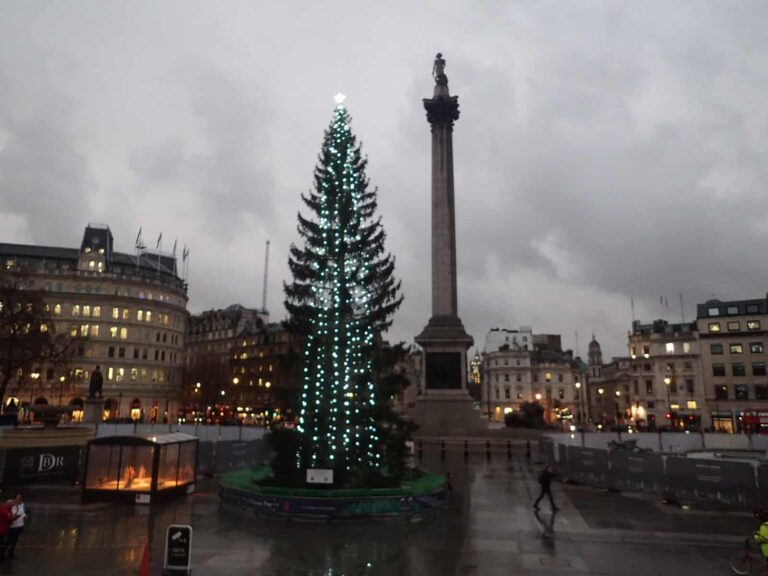 Le sapin de Noël illuminé de Trafalgar Square au crépuscule, avec la colonne Nelson et les façades de la place en arrière-plan