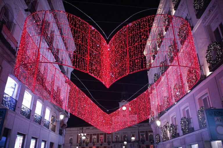 Une grande illumination rouge en forme de cœur suspendue au-dessus de la calle de Preciados, entre des façades décorées de couronnes