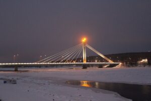 Le pont de la Bougie du bûcheron, à Rovaniemi, éclairé à la tombée de la nuit au-dessus de la rivière Kemijoki prise par les glaces