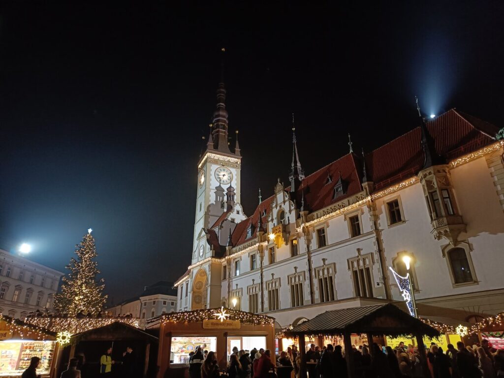 L’hôtel de ville d’Olomouc illuminé, le sapin de Noël et les chalets du marché sur la place Horní, de nuit