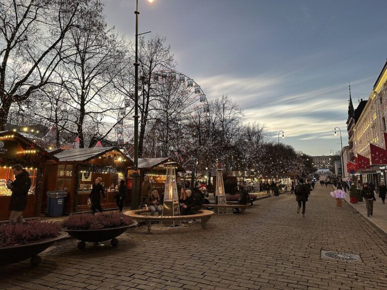 L’allée de chalets du marché de Noël de Karl Johans gate à la tombée de la nuit, avec la grande roue au fond