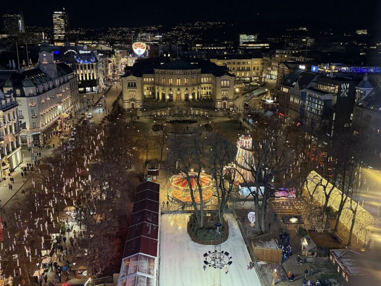 Vue plongeante de nuit sur Spikersuppa, la patinoire, les chalets du marché de Noël et le Parlement norvégien