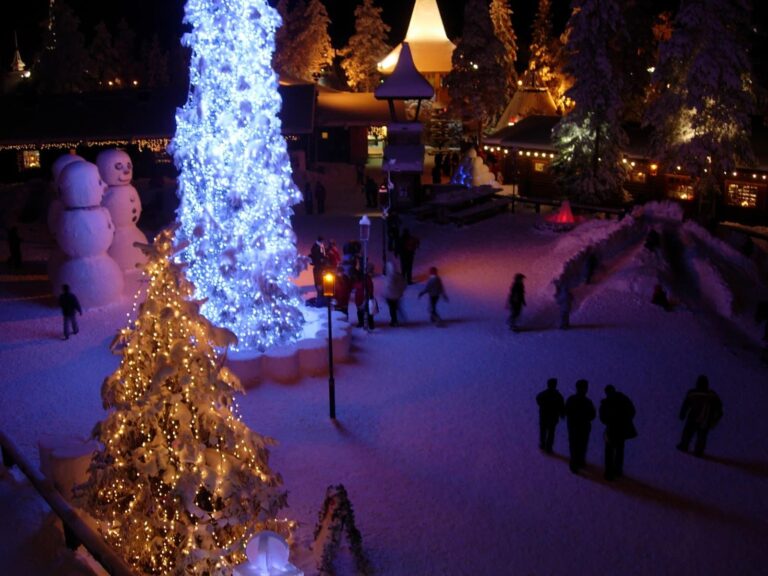 Le Santa Claus Village de nuit, un sapin couvert de lumières et des bonshommes de neige sur la place enneigée, à Rovaniemi