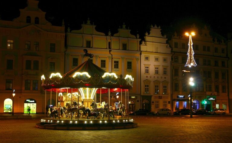 Un carrousel illuminé sur la place de la République de Plzeň, la nuit, devant les façades à pignons et un sapin lumineux