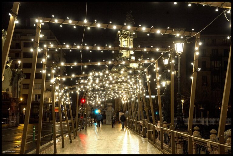 Le pont María Cristina sur l’Urumea couvert d’une voûte de guirlandes d’ampoules, de nuit, avec quelques passants au loin
