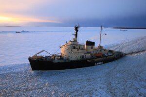 Le brise-glace Sampo, coque noire et superstructure crème, immobile dans la mer gelée au large de Kemi, au coucher du soleil