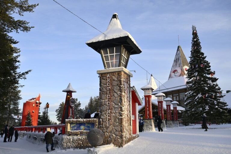 Les lanternes de pierre et de bois qui jalonnent la ligne du cercle polaire, devant un grand sapin et le bâtiment du bureau du Père Noël