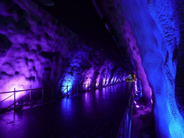 Le tunnel creusé dans la roche qui descend vers la grotte de SantaPark, éclairé de violet et de bleu