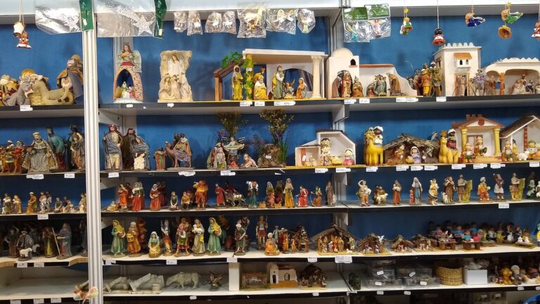 Les étagères d’un stand de la Feria del Belén de Séville : santons, rois mages, crèches et maisonnettes blanches sur fond bleu