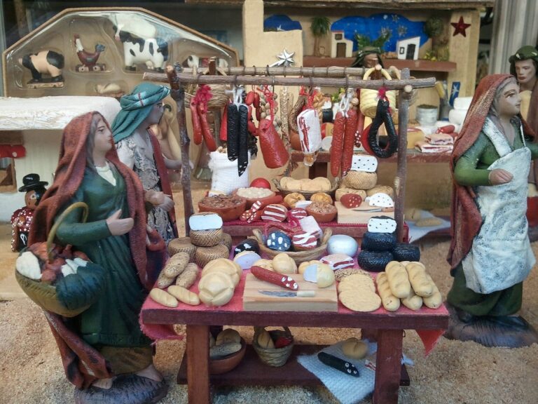 Une scène de crèche sévillane : deux villageoises en terre cuite devant un étal de pain, de fromages et de charcuterie miniatures
