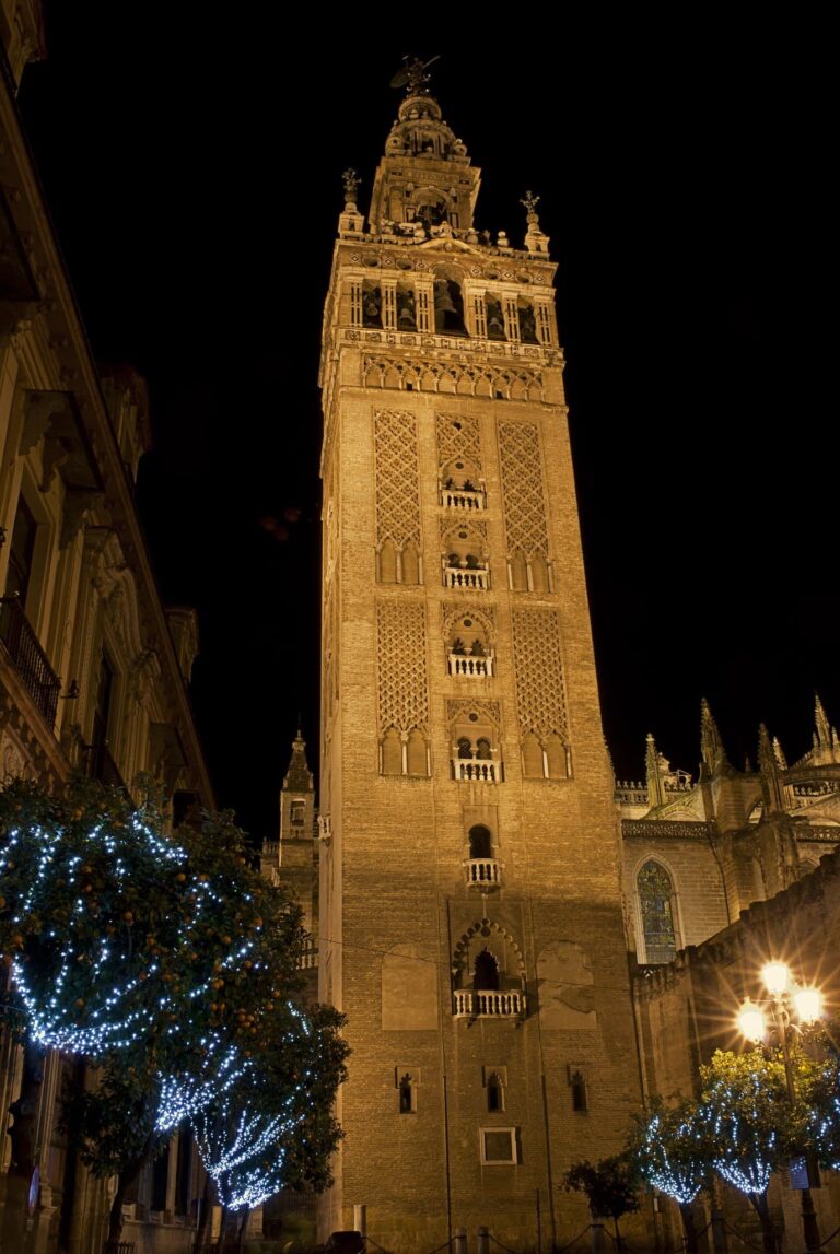 La Giralda éclairée la nuit, avec des arbres garnis de guirlandes bleues au premier plan