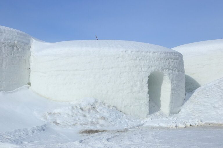Les voûtes de neige du SnowVillage de Lainio et l’une de leurs entrées, sous un ciel bleu