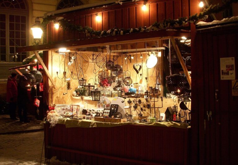 Un chalet rouge éclairé de nuit, rempli de lanternes et d’objets en fer forgé, au marché de Noël de Stortorget