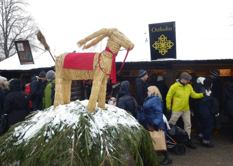 Un bouc de Noël en paille couvert de neige devant les étals du marché de Noël de Skansen