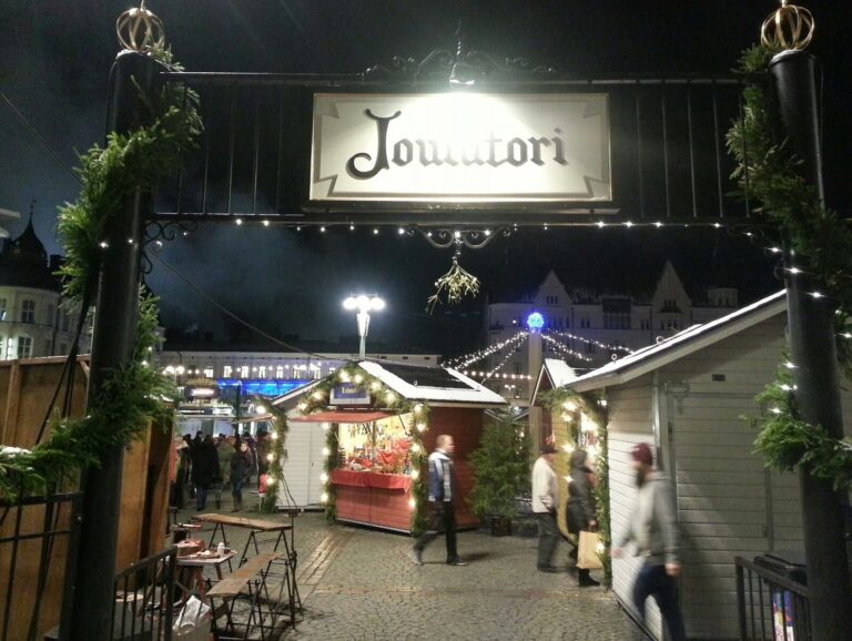 Le portique « Joulutori » à l’entrée du marché de Noël de Tampere de nuit, guirlandes lumineuses et chalets décorés derrière