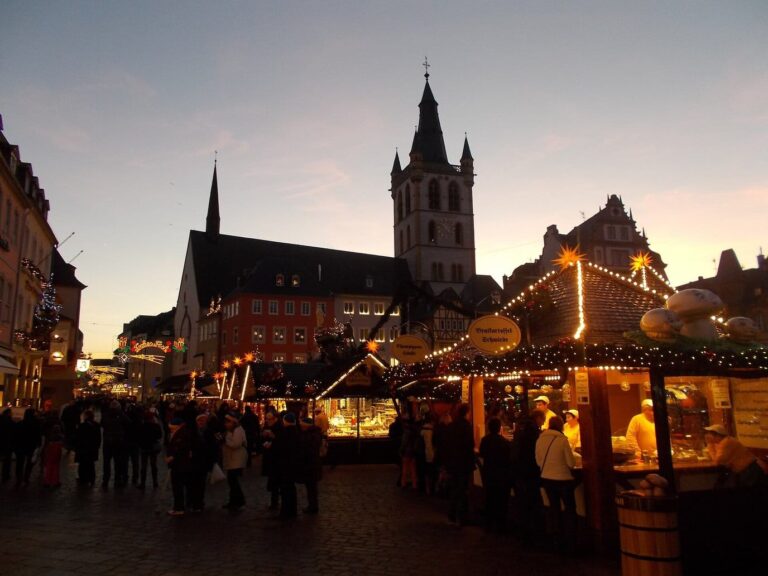 Le marché de Noël du Hauptmarkt à la tombée du jour, chalets illuminés et clocher de Saint-Gangolf sur un ciel rosé