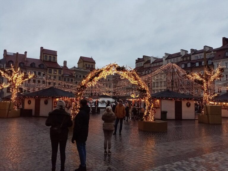 Des arches de lumière et des guirlandes au-dessus des chalets du marché de Noël de la vieille ville de Varsovie, de nuit