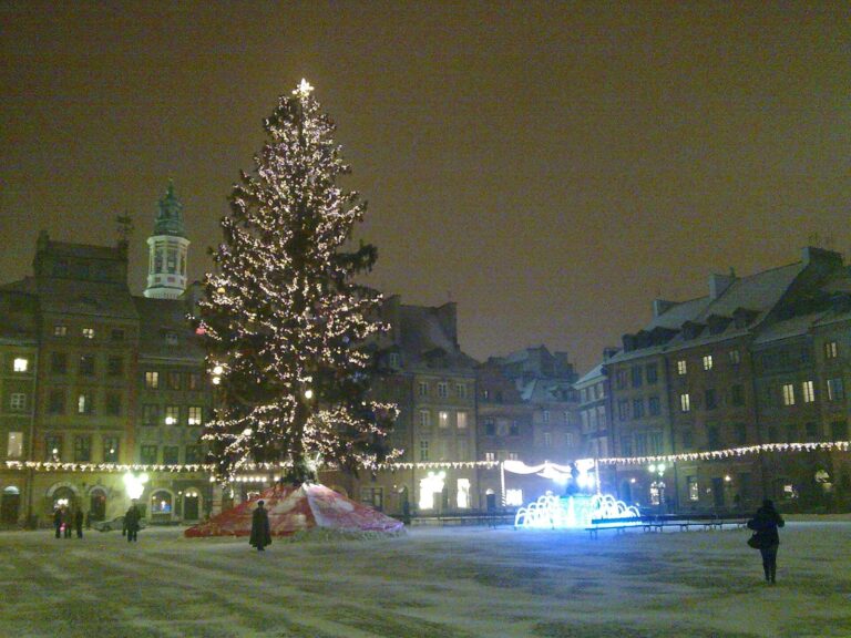 La place du Marché de la vieille ville de Varsovie de nuit, avec son grand sapin illuminé, la fontaine lumineuse et les façades éclairées