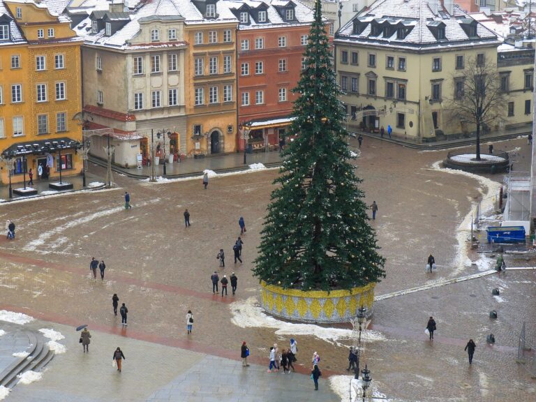 La place du Château de Varsovie vue d’en haut en hiver, avec ses toits enneigés, un grand sapin de Noël et la colonne de Sigismond