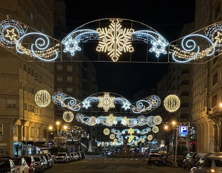 Une enfilade d’arches lumineuses ornées de flocons et de volutes au-dessus d’une avenue de Vigo, de nuit