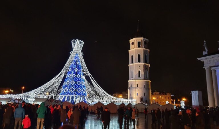 Le sapin bleu et blanc de la place de la Cathédrale de Vilnius, éclairé de nuit, avec le campanile et la foule