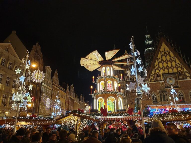 La grande pyramide de Noël du marché de Wrocław, de nuit, entre les chalets décorés